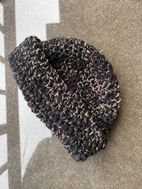 a black knitted beanie on a concrete floor